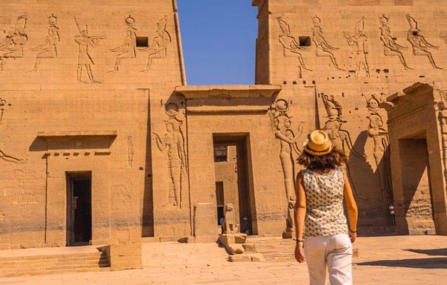 Visitor walking towards the carved first pylon of Philae Temple