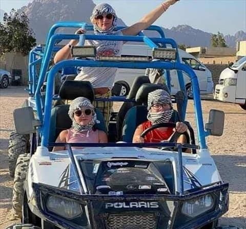 Family with two children in desert scarves sitting in a four-seat buggy before the safari