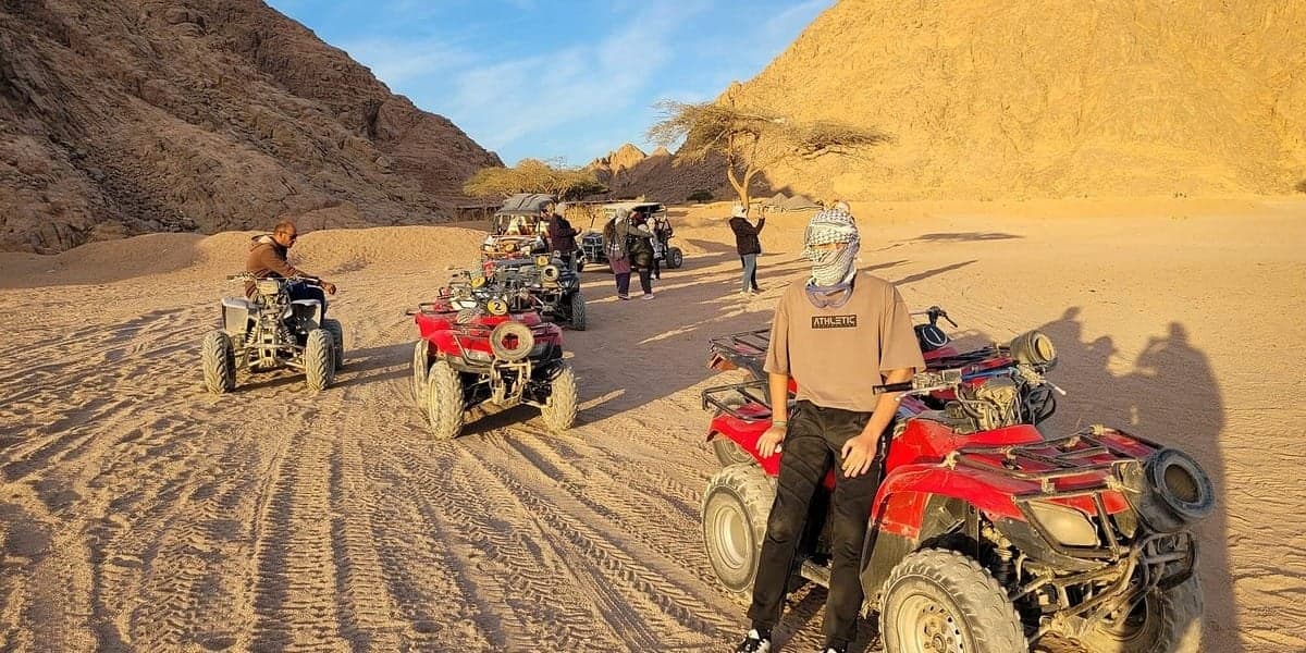 Marsa Alam desert safari: guests with quad bikes in a sandy desert valley between rocky mountains