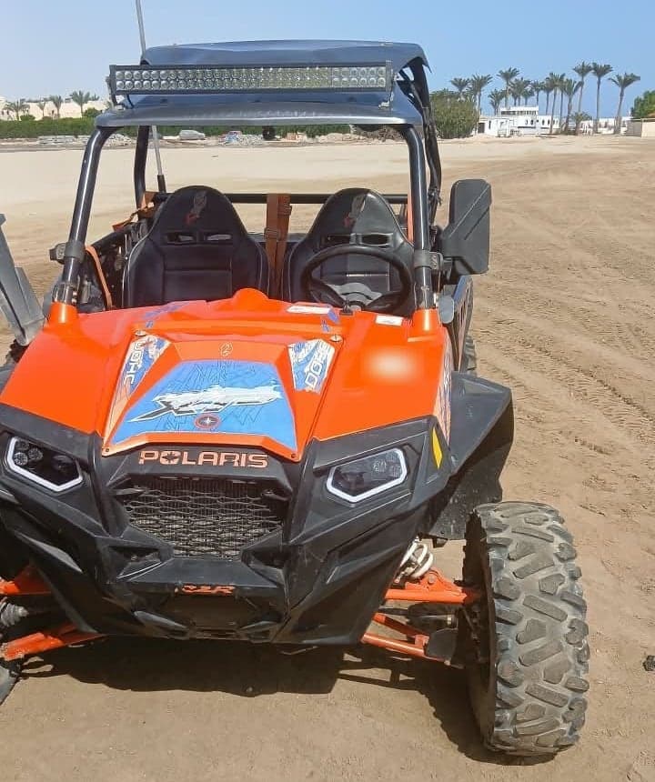 Front view of a two-seat desert buggy with roof light bar on the sand in Marsa Alam